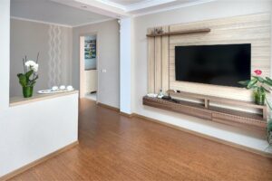 Modern living room with warm wood flooring and built in media wall showing durable hard surface flooring in a stylish home interior