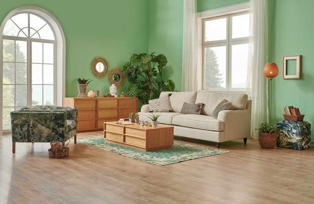 Bright living room with green walls, wood flooring, and a low pile area rug defining the seating area in an open living space