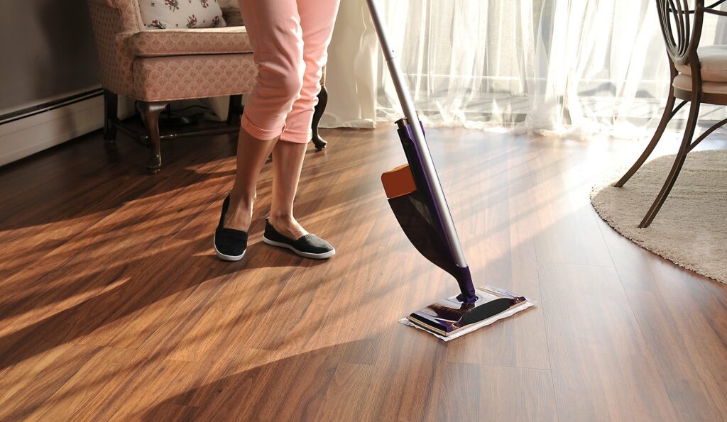 person cleaning hardwood or vinyl plank flooring with mop in sunlit living room durable easy clean flooring for busy homes