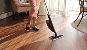 person cleaning hardwood or vinyl plank flooring with mop in sunlit living room durable easy clean flooring for busy homes