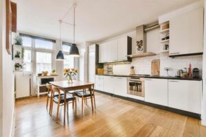 modern kitchen with white shaker cabinets hardwood flooring black countertops pendant lighting and dining area in open concept home