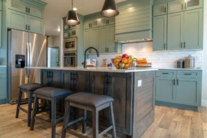 two tone kitchen design with sage green cabinets dark wood island quartz countertops and luxury vinyl plank flooring