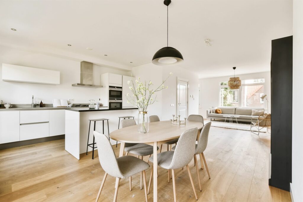 modern open concept kitchen with white cabinets black countertops light wood flooring and dining area