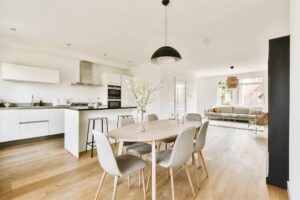 modern open concept kitchen with white cabinets black countertops light wood flooring and dining area