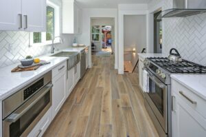 white shaker kitchen with quartz countertops herringbone tile backsplash and wood look vinyl flooring